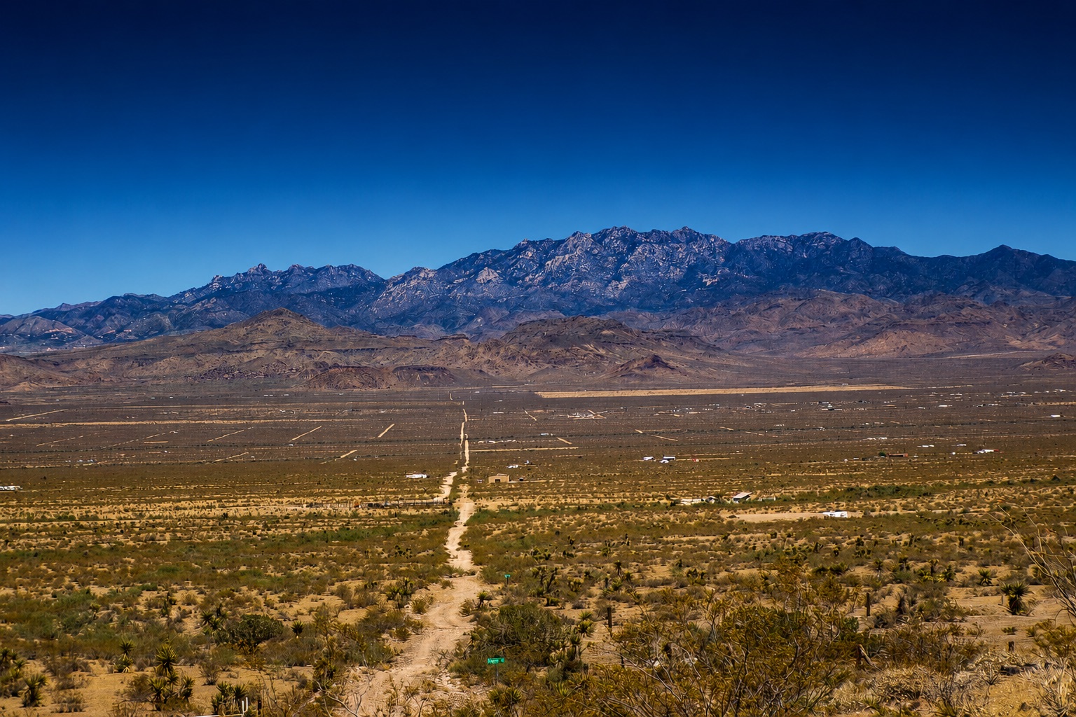 Arizona desert land with mountain range under a clear blue sky
